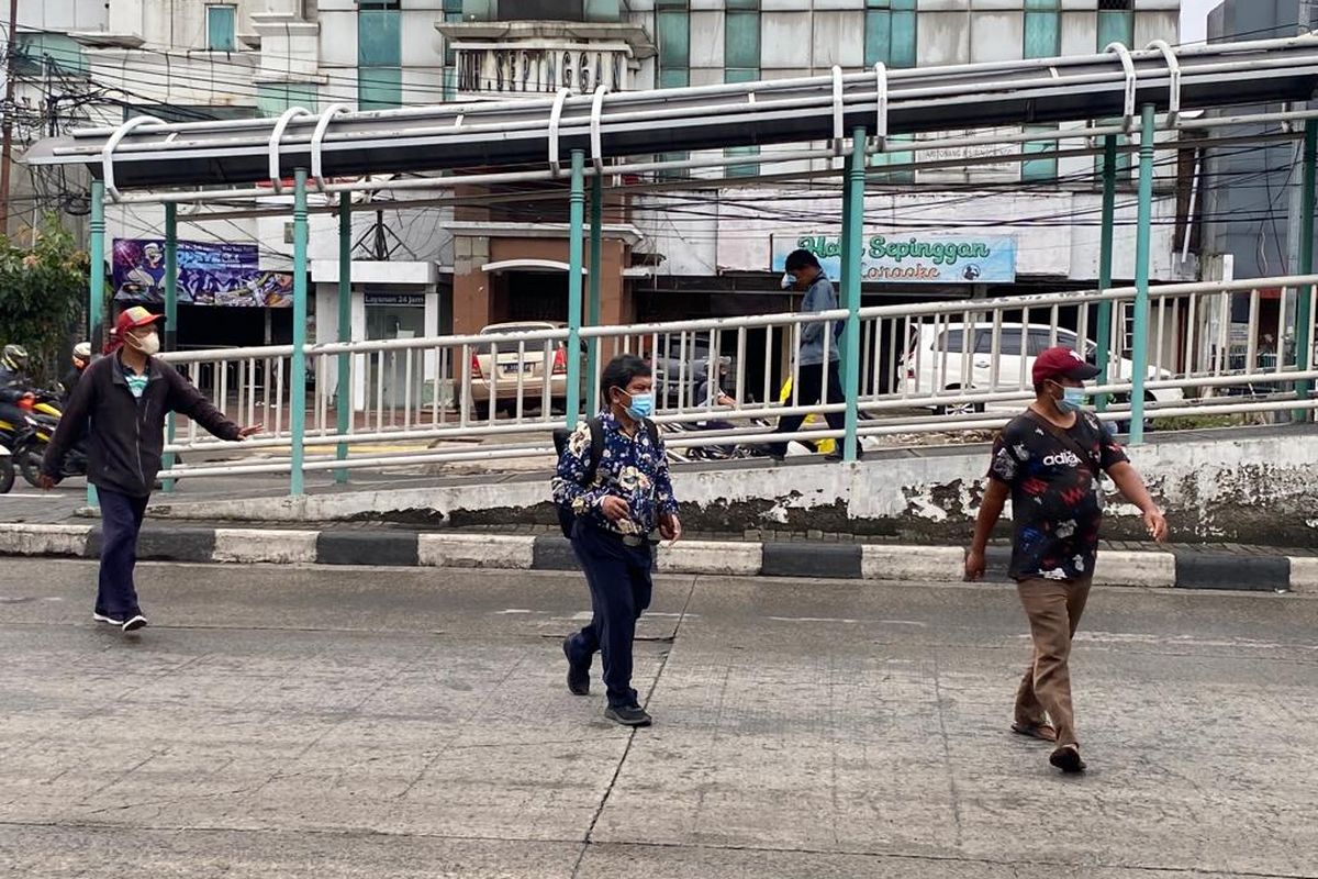 Warga menyeberang di Jalan Enggano Raya, Tanjung Priok, Jakarta Utara, Rabu (22/2/2023). Di jalan ini, tak ada akses penyeberangan yang laik untuk warga. 