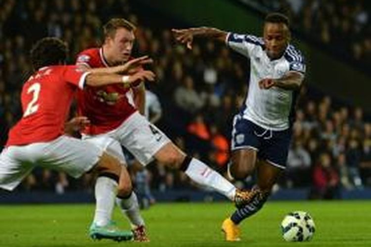 Striker West Bromwich Albion, Saido Berahino (kanan), mencoba melewati hadangan dua pemain Manchester United, Rafael (kiri) dan Phil Jones (tengah), pada laga di The Hawthorns, Senin (20/10/2014).