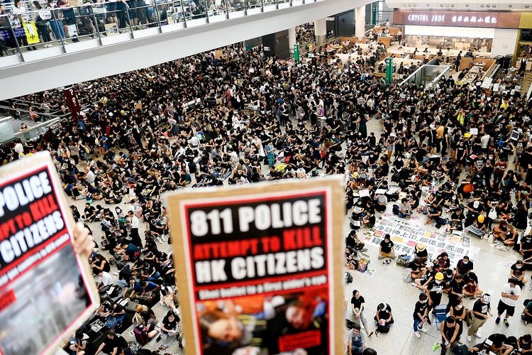 Massa pengunjuk rasa memadati aula kedatangan di Bandara Internasional Hong Kong, Senin (12/8/2019). Pengunjuk rasa yang mencapai lebih dari 5.000 orang memaksa dihentikannya operasional bandara.