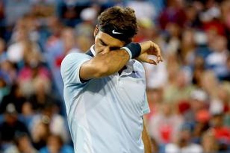 Petenis Swiss, Roger Federer, mengelap mukanya saat bertanding melawan Rafael Nadal dari Spanyol, di Western & Southern Open, Cincinnati, Jumat (16/8/2013).