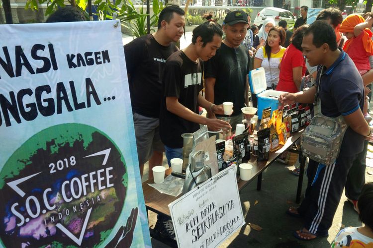 Pengunjung CFD Solo, Jawa Tengah, menikmati secangkir kopi yang disajikan para barista dalam aksi galang dana bantuan korban gempa dan tsunami Donggala-Palu di Solo, Minggu (7/10/2018). 