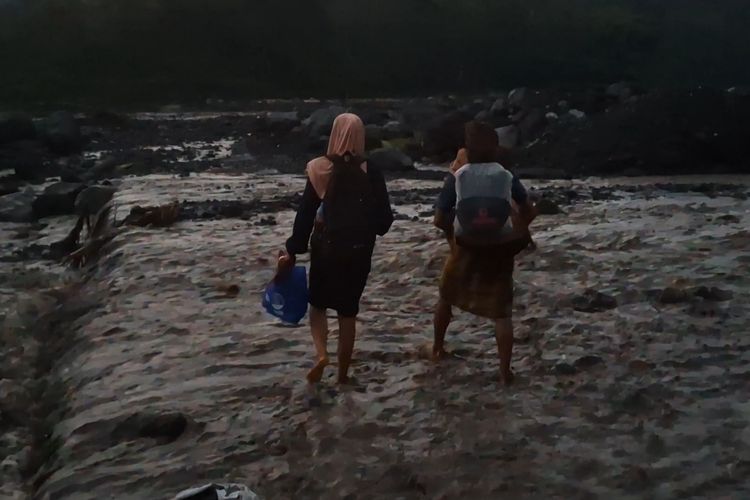 Sintia menyebrangi banjir lahar hujan Gunung Semeru digendong tetangganya, Jumat (17/1/2025)