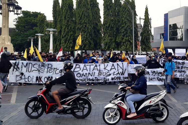 Massa aksi membentangkan spanduk dalam unjuk rasa menolak Undang-Undang (UU) Cipta Kerja di Solo, Jawa Tengah, Kamis (8/10/2020) sore.