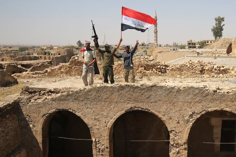 Pejuang milisi di Irak mengangkat bendera Irak usai memenangi sebuah operasi melawan ISIS di Tal Afar.