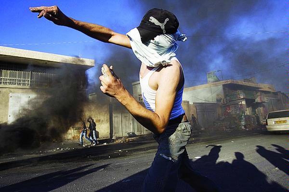 Pemuda Palestina bertopeng melempari aparat Israel dengan batu dalam bentrokan yang terjadi di kamp pengungsi Shuafat di Jerusalem timur, Senin (5/10). Polisi menyerbu Kota Tua Jerusalem setelah terjadi cekcok di dekat kompleks Masjid Al Aqsa saat sekitar 10.000 warga Yahudi Israel melakukan ritual keagamaan di dekat kompleks itu.