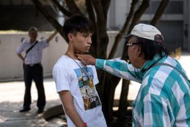 Seorang pria menusukkan jarinya ke leher salah seorang pengunjuk rasa pro-demokrasi Hongkong, Senin (13/10/2014).