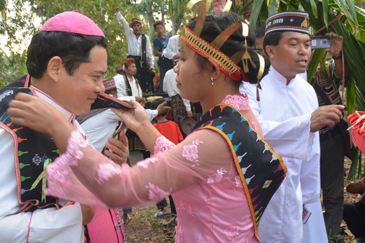 Seorang perempuan Kampung Noa, Desa Golondoal, Kecamatan Mbeliling, Kabupaten Manggarai Barat, Flores, NTT, September 2018 lalu mengalunkan kain selendang songke kepada Uskup Denpasar merangkap Administrator Apostolik Keuskupan Ruteng, Mgr. Silvester San bersama rombongannya. (KOMPAS.com/Markus Makur)