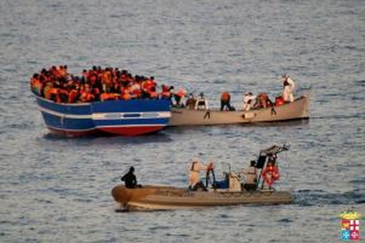 Dalam foto yang dirilis AL Italia pada 2 April 2014 ini terlihat pra imigran ilegal sedang dibantu pasukan AL Italia saat diselamatkan dari Laut Tengah.

