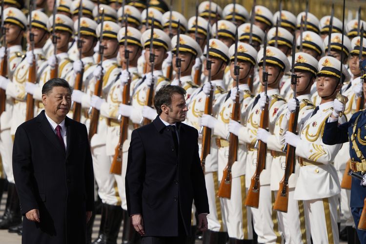 Presiden Perancis Emmanuel Macron memeriksa pasukan kehormatan bersama Presiden China Xi Jinping di luar Aula Besar Rakyat di Beijing, Kamis (6/4/2023).