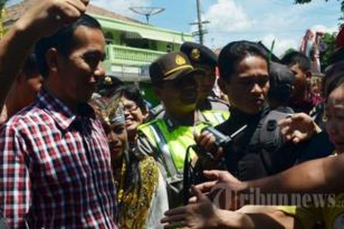 Gubernur DKI Jakarta Joko Widodo (kemeja kotak-kotak) mengikuti kampanye calon gubernur Jawa Timur, Bambang Dwi Hartono di Pasar Sayur Magetan, Minggu (18/8/2013).