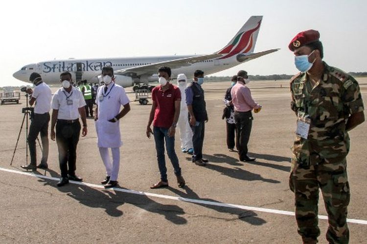 Pejabat bandara, anggota staf, dan personel keamanan berdiri di samping pesawat SriLankan Airlines yang membawa 33 warga negara Sri Lanka yang dievakuasi dari kota Wuhan di China setelah mendarat di Bandara Internasional Mattala Rajapaksa di Mattala pada 1 Februari 2020. Virus yang mirip dengan SARS patogen telah membunuh 259 orang di China dan menyebar ke seluruh dunia sejak muncul di sebuah pasar di pusat kota Wuhan di China. 