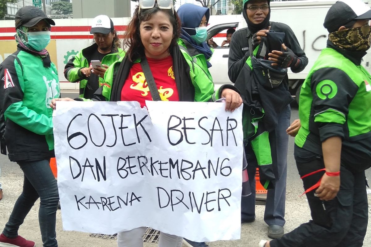 Salah satu pengedara ojol menunjukkan poster bertuliskan Gojek Besar dan Berkembang Karena Driver. Hal tersebut dilakukan saat pengemudi Gojek menggelar aksi di depan gedung Kedubes Malaysia, Jalan Rasuna Said, Jakarta Selatan, Selasa (3/9/2019)