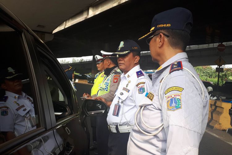 Mobil berplat genap dihentikan polisi dan petugas Sudin Perhubungan Jakarta Timur saat melintas di Simpang Perintis Kemerdekaan, Cempaka Putih