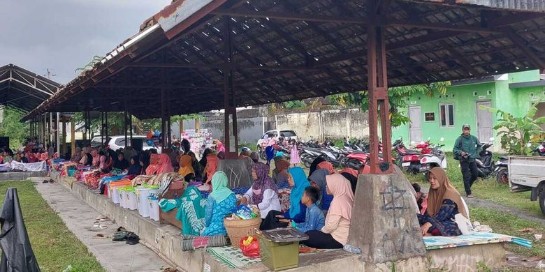 Para warga perempuan di Padukuhan Saren, Kalurahan Wedomartani, Kapanewon Ngemplak, Kabupaten Sleman saat mengikuti acara tradisi Nyadran Pasar. Mereka duduk di los Pasar Wonosari dan tepat didepanya terdapat berbagai makanan yang dibawa dari rumah untuk disantap oleh warga bersama-sama.