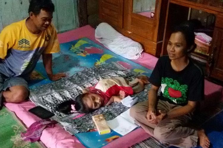 Rusmiyati menunggui anaknya, Arista yang tergolek lumpuh sejak usia dua tahun di rumahnya di Desa Sumbergandu, Kecamatan Pilangkenceng, Kabupaten Madiun, Senin (13/3/2017) siang.
