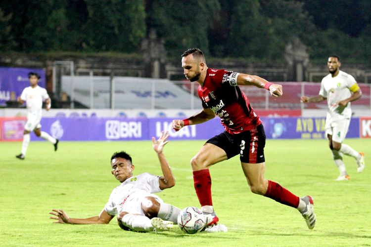 Pemain Bali United Ilija Spasojevic dihentikan pemain Persebaya Surabaya Rizki Ridho saat pertandingan pekan 33 Liga 1 2021-2022 yang berakhir dengan skor 0-3 di Stadion I Gusti Ngurah Rai Denpasar, Jumat (25/3/2022) malam.