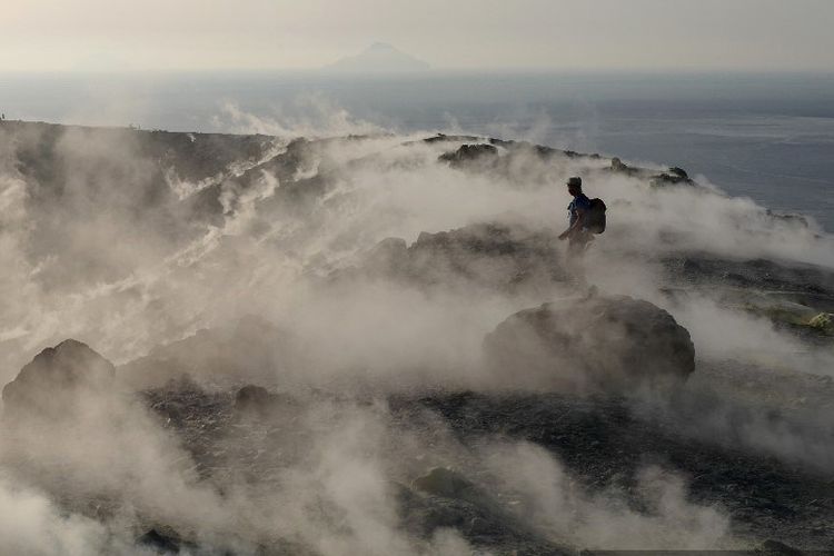 Seorang turis berjalan di fumarol sebuah kawah di pulau vulkanik Vulcano, salah satu Kepulauan Aeolian, di Laut Tyrrhenian, Italia, pada 19 September 2019. 