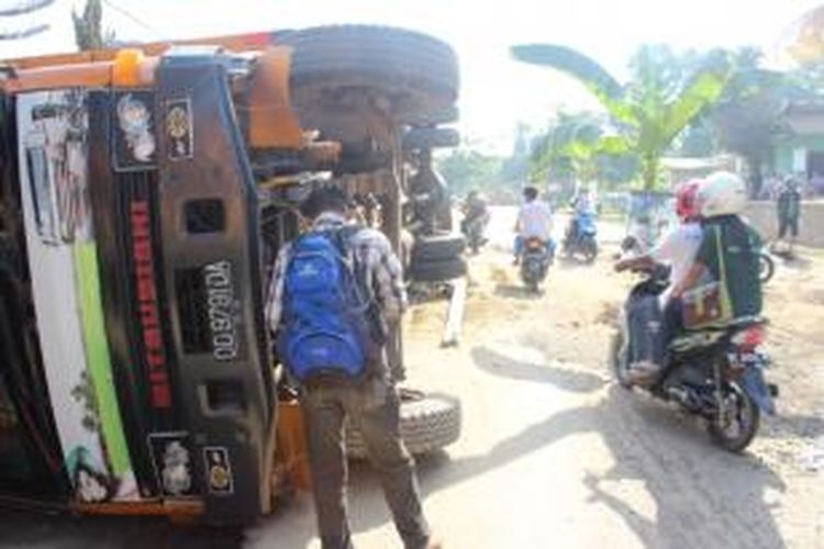 Sebuah truk bermuatan pakaian bekas terbalik di ruas jalan trans Sulawesi, akibat jalan rusak dan berlubang
