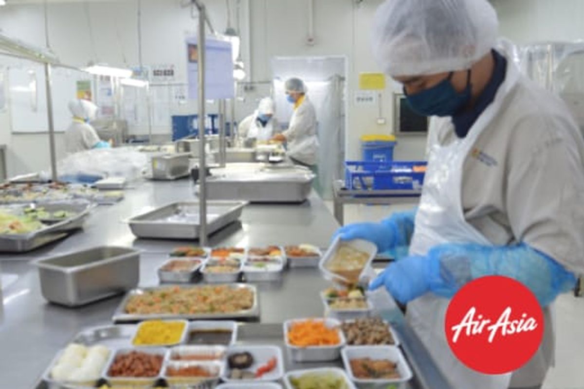 Staf produksi inflight meals AirAsia menggunakan APD dalam menyiapkan pesananan makanan untuk penumpang.