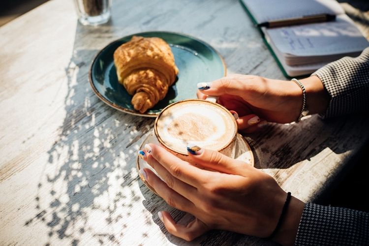Ilustrasi food photography secangkir cappuccino dan croissant di sebuah kafe.