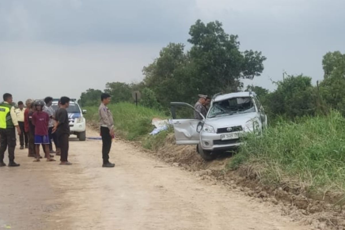 Petugas kepolisian dan warga saat mengevakuasi mobil masuk kanal di Jalan Koridor PT RAPP, di Kabupaten Pelalawan, Riau, Senin (12/1/2026).