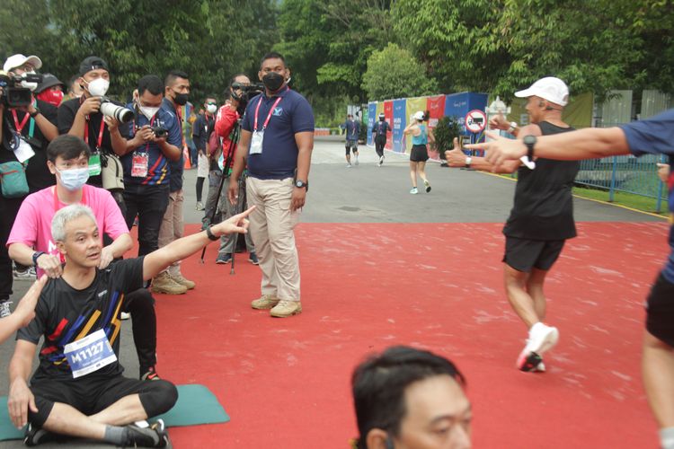 Gubernur Jawa Tengah, Ganjar Pranowo, duduk bersila menyemangati sekaligus menggoda peserta Tilik Candi Borobudur Marathon, Minggu (28/11/2021) di Kompleks Taman Lumbini, Candi Borobudur.
