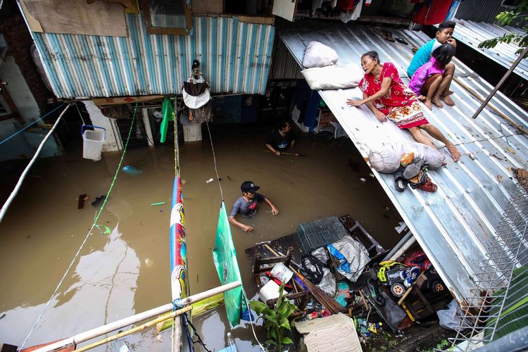 Warga menggunakan atap untuk berlindung sebelum di evakuasi saat banjir di Jalan Karet Pasar Baru, Karet Tengsin, Jakarta Pusat, Selasa (25/2/2020). Hujan deras sejak Senin dini hari membuat sejumlah daerah di Ibu Kota tergenang banjir.