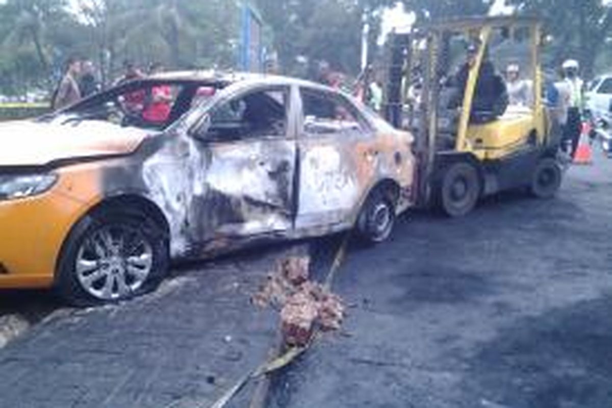 Polisi menggunakan forklift untuk mengevakuasi mobil yang terbakar di Bintaro, Tangerang Selatan, Selasa (12/8/2014).