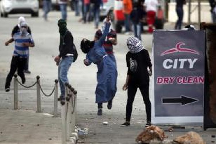 Perempuan Palestina berunjuk rasa dengan melempar batu ke arah tentara Israel saat terjadi bentrokan di Beit El, dekat Ramallah, Tepi Barat, 8 Oktober 2015.