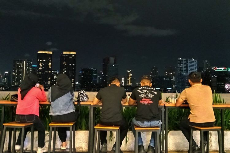 Pengunjung kafe rooftop Kuningan City Mall melihat pemandangan city light malam hari.