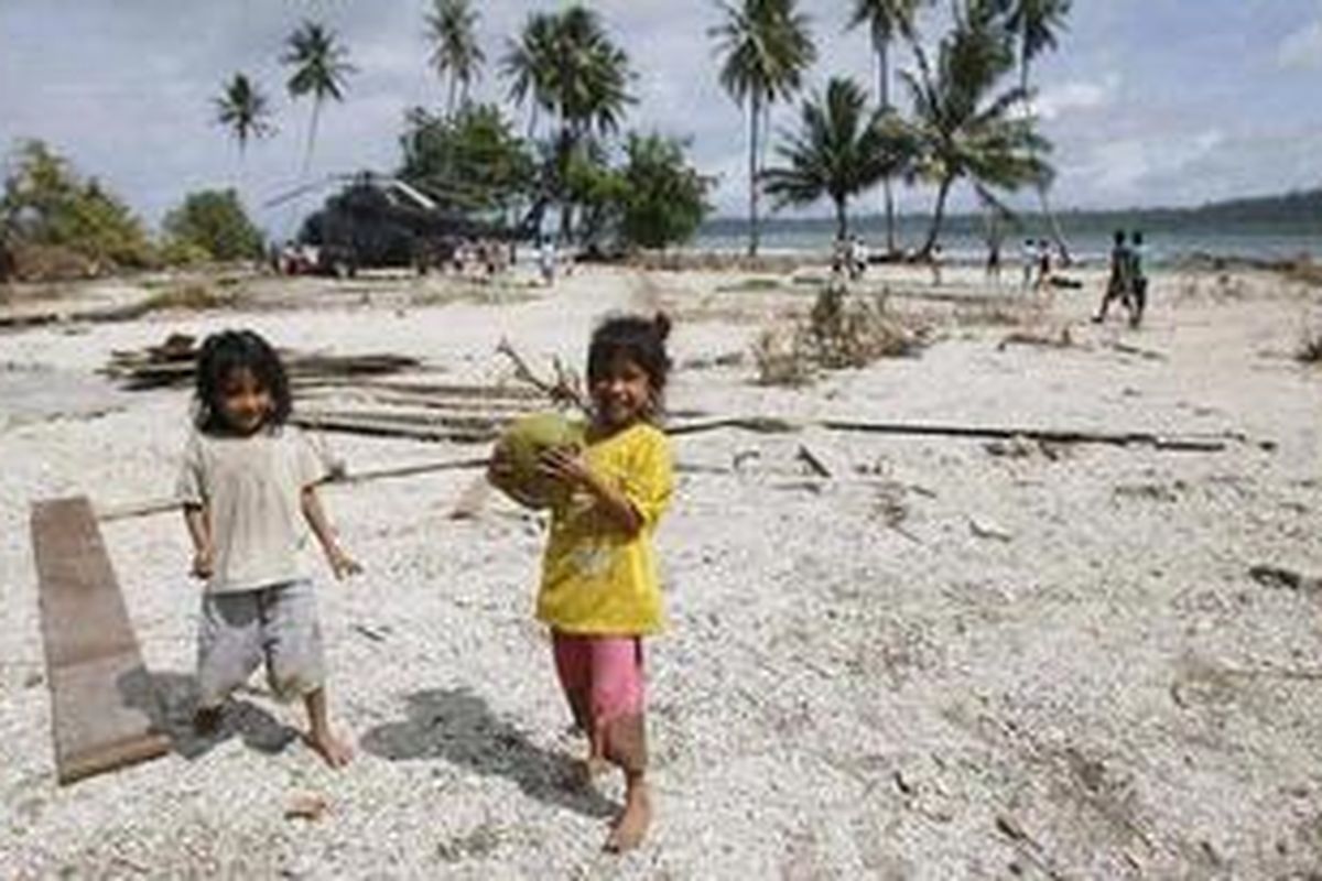Anak kembar, Nila dan Lili (4) membawa buah kelapa untuk mereka minum airnya dari pohon kelapa di sekitar reruntuhan bangunan yang tersapu tsunami di Kampung Tumalei, Desa Silabu Kecamatan Saumanganya, Kabupaten Kepulauan Mentawai, Sumatera Barat, Minggu (31/10/2010). Warga meminum air kelapa sementara bantuan air bersih belum tiba. Mereka pun masih menggunakan air kotor karena sulitnya mendapatkan air bersih untuk kebutuhan MCK. 