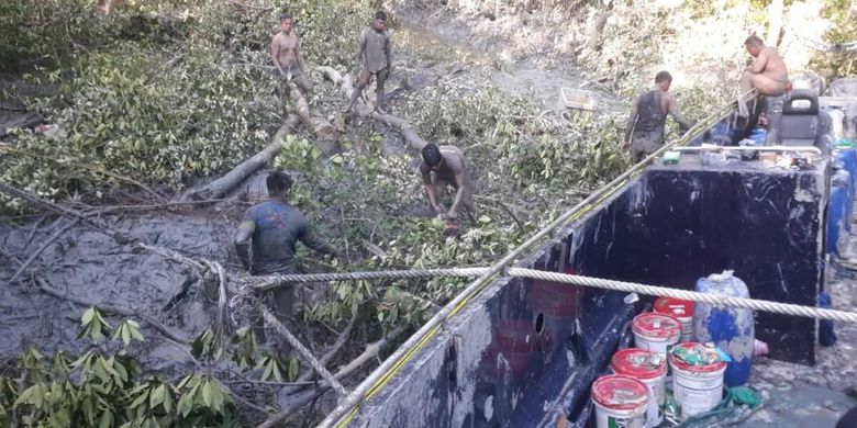 Polisi bergelimang lumpur saat proses evakuasi kapal hantu di hutan bakau Padang Jati OKI, Sumsel, Jumat (11/6/2021).