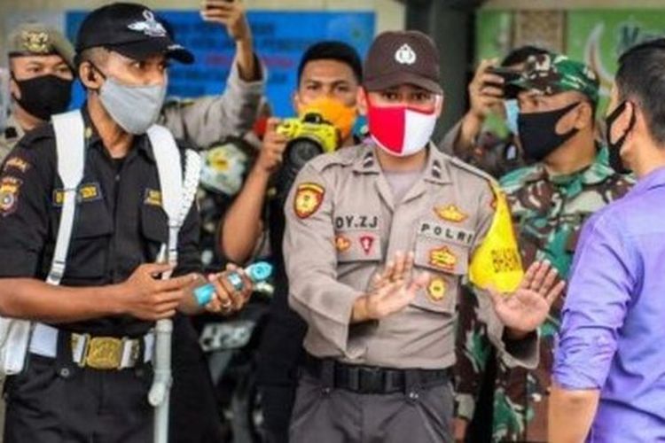 Polisi menjelaskan tentang hasil pengukuran suhu tubuh yang tinggi kepada seorang pengunjung mal saat simulasi protokol kesehatan pencegahan penyebaran Covid-19 di Lhokseumawe, Aceh, Jumat (29/05). Simulasi itu dilakukan untuk memperketat penerapan protokol kesehatan. 