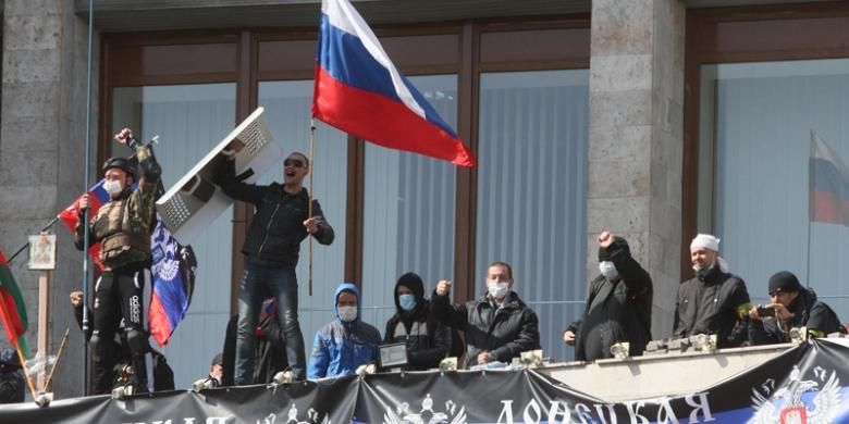 Seorang aktivis mengibarkan bendera Rusia di balkon sebuah gedung pemerintah yang mereka duduki di kota Donetsk, Ukraina setelah proklamasi kemerdekaan kota tersebut.