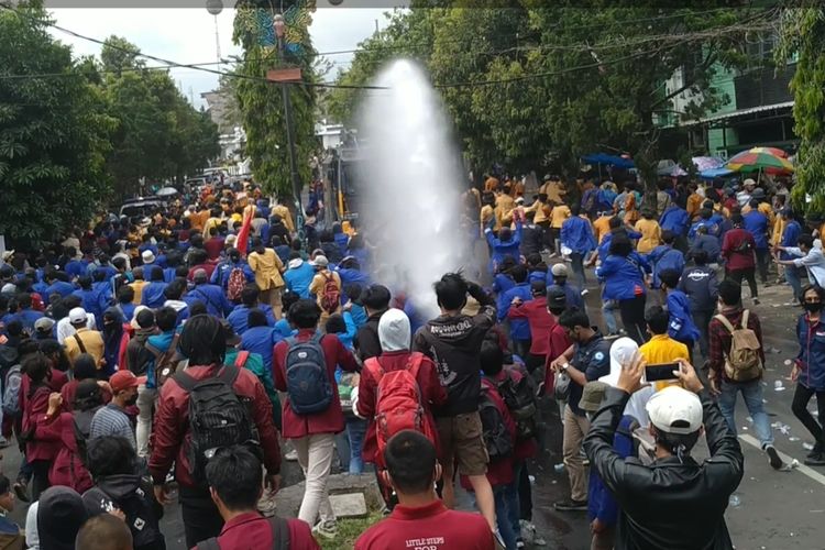 Sejumlah mahasiswa berlarian saat water cannon menyenmprotkan air saat demonstrasi mahasiswa menolak omnibus law di depan Gedung DPRD Kota Sukabumi, Jawa Barat, Kamis (8/10/2020).