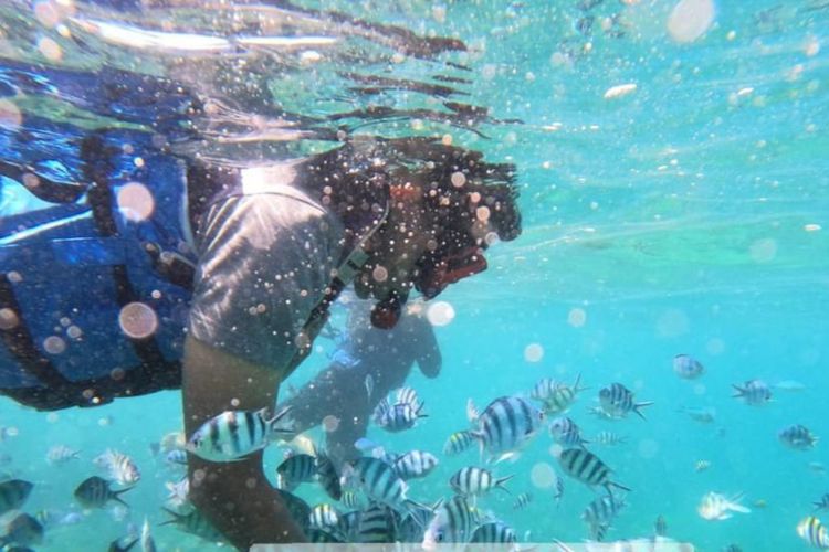 Pengunjung merasakan sensasi mandi ikan di laut Belitung, Bangka Belitung, Rabu (26/4/2023).