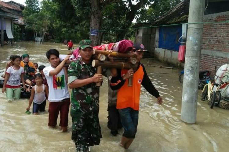 Anggota TNI bersama warga saat mengevakuasi salah seorang warga Desa Sayung,  Kabupaten Demak,  Jateng,  yang mengalami kejang kejang akibat kedinginan dampak banjir yang melanda wilayah tersebut,  Selasa (14/2/2017)