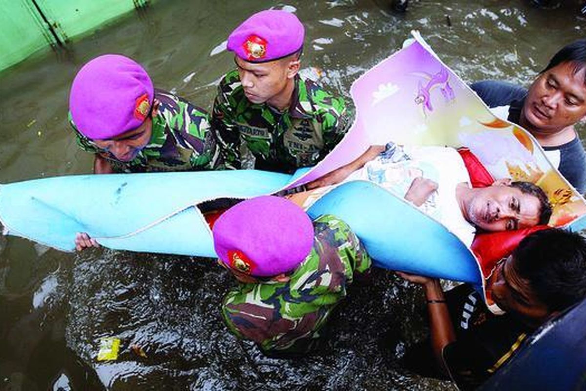 Personel Marinir TNI AL  dan warga mengevakuasi korban banjir yang sakit saat mereka membagikan bantuan di kawasan Kali Pasir, Penjaringan, Jakarta Utara, Minggu (20/1). Selain membutuhkan makanan, masyarakat yang terkena bencana banjir juga membutuhkan air bersih dan kebutuhan lainnya.
