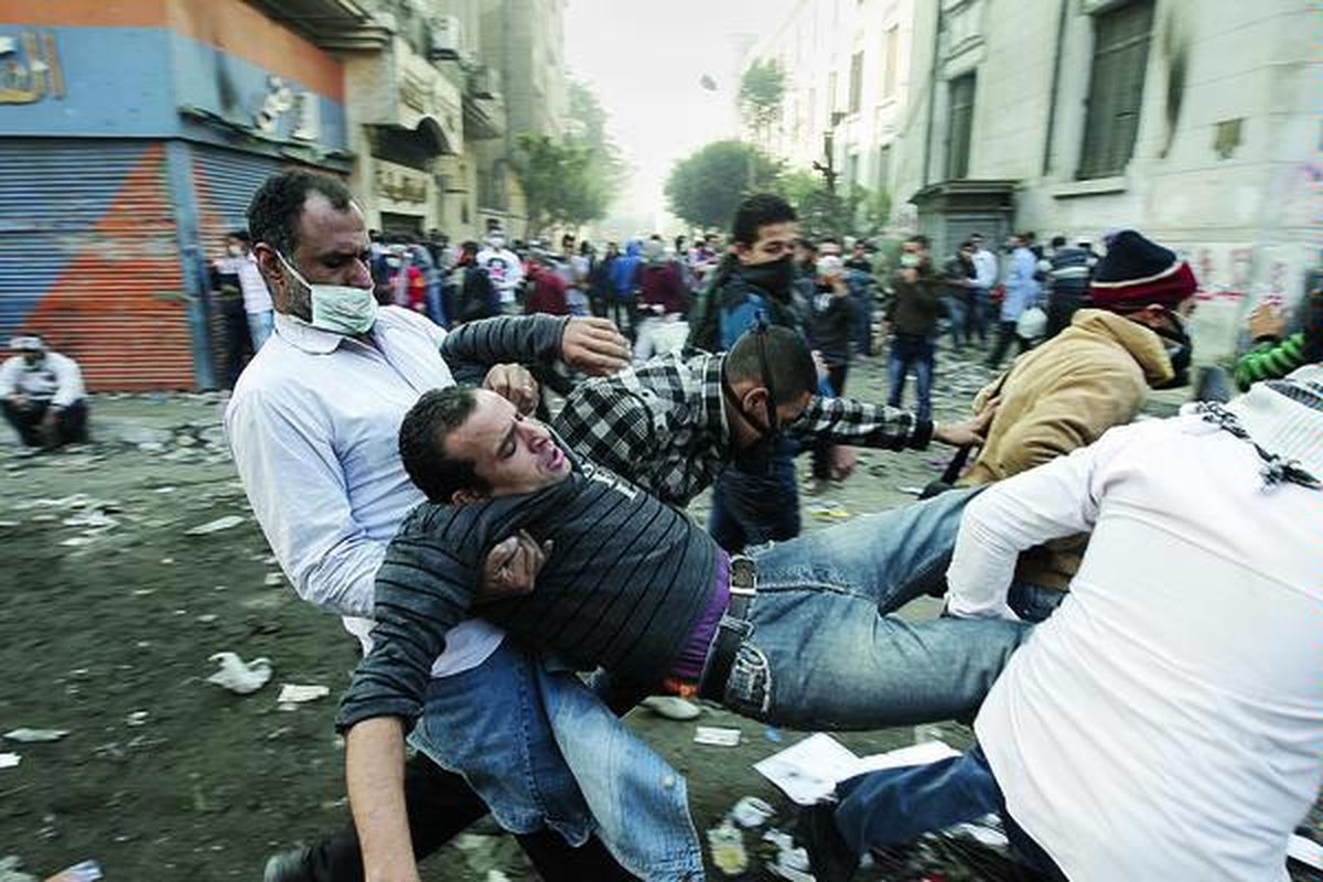 Demonstran yang terluka dibawa pergi oleh rekan-rekannya dalam bentrokan dengan polisi Mesir di jalan menuju Kementerian Dalam Negeri, dekat Alun-alun Tahrir, Kairo, Rabu (23/11). Ribuan demonstran menuntut mundurnya Dewan Agung Militer meskipun penguasa sementara Mesir itu berjanji menyerahkan kekuasaan pada Juni 2012.