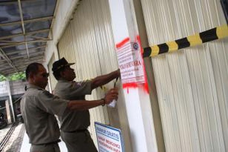 Petugas Satuan Polisi Pamong Praja Kabupaten Bogor, menyegel minimarket yang tak mengantongi izin di wilayah Kecamatan Cibinong, Kabupaten Bogor, Selasa (20/5/2014). K97-14