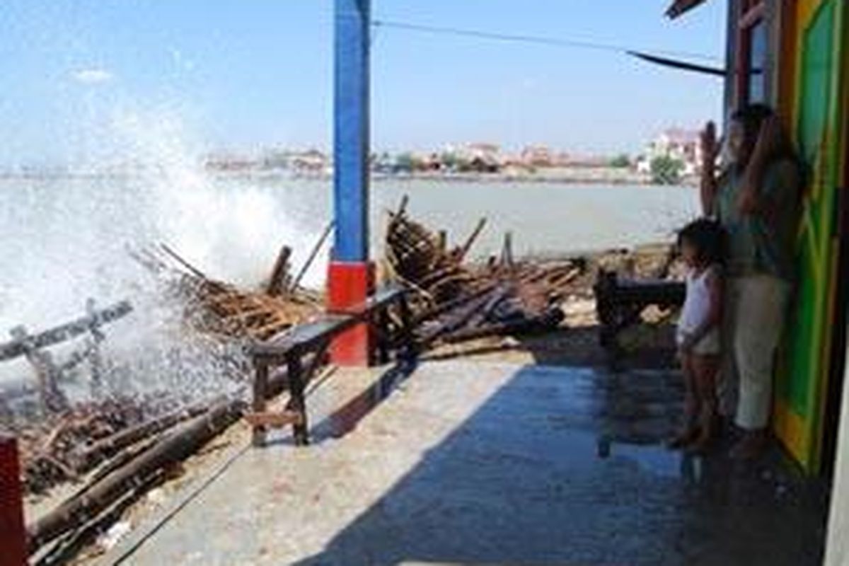 Kamirah (33) dan Sania (6), warga Dukuh Karanggeneng, Desa Tanjungsari, Kecamatan Rembang, Kabupaten Rembang, Jawa Tengah, melihat deburan ombak pasang dari serambi rumah, Selasa (8/7) siang. Sejak 10 hari lalu, ombak pasang mengancam permukiman penduduk di pesisir Rembang. Di Dukuh Karanggeneng, deburan ombak melimpas ke serambi dan halaman belakang rumah 10 warga.