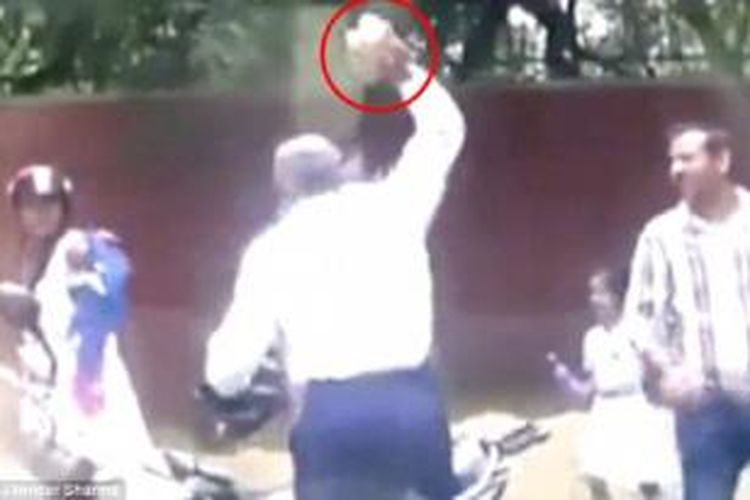 Seorang pelintas merekam adegan saat seorang polisi di New Delhi, India, melemparkan batu bata ke seorang perempuan yang tampaknya tidak mau membayar suap sebesar Rp 40.000 buat polisi tersebut.