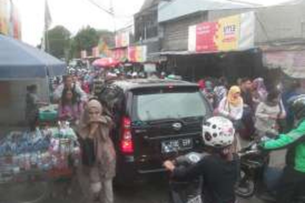 Sebuah mobil yang tengah terjebak kepadatan manusia di jalan akses Stasiun Depok. Banyaknya penumpang KRL yang berangkat dari Stasiun Depok menyebabkan jalan akses penghubung ini menjadi sangat padat oleh manusia. Kondisi jalan akses yang sempit, ditambah dengan kepadatan manusia membuat mobil sebenarnya tak cukup leluasa untuk bergerak. 