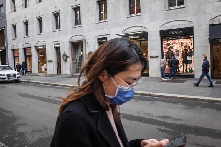 Seorang perempuan mengenakan masker berjalan di jalan Montenapoleone yang hampir kosong, salah satu jalan distrik mode Milan, Italia EPA-EFE/MATTEO CORNER