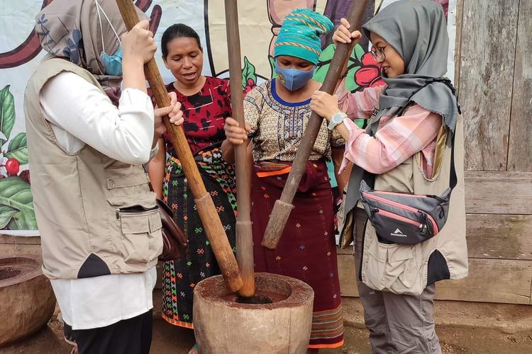 Dua dosen Ekowisata Universitas Bina Nusantara Jakarta sedang berwisata di kedai kopi Tuk sambil mempraktekan cara menumpuk kopi dengan peralatan kayu bersama kaum perempuan di tempat itu, Senin, (28/3/2022).  (digitren.id/DOK PEMANDU WISATA-MUHAMMAD BOEHARTO)