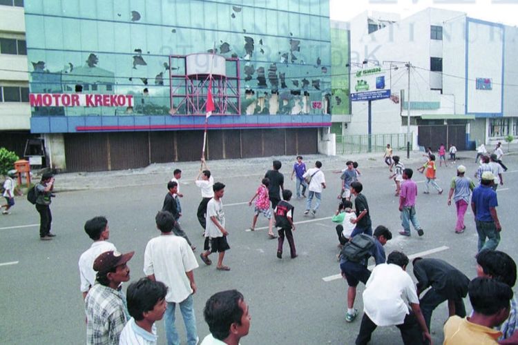 Sejumlah remaja tengah melempar sebuah agen penjualan mobil di Krekot, Jakarta Pusat, pada hari kerusuhan dan penjarahan massal tanggal 14 Mei.