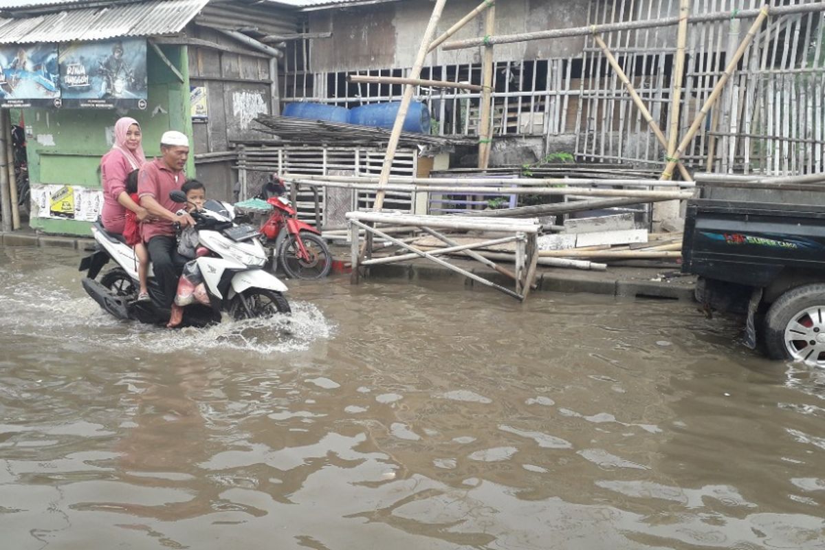Sepeda motor melintasi sebuah jalan di kawasan Muara Angke yang terendam banjir rob, Senin (21/1/2019).