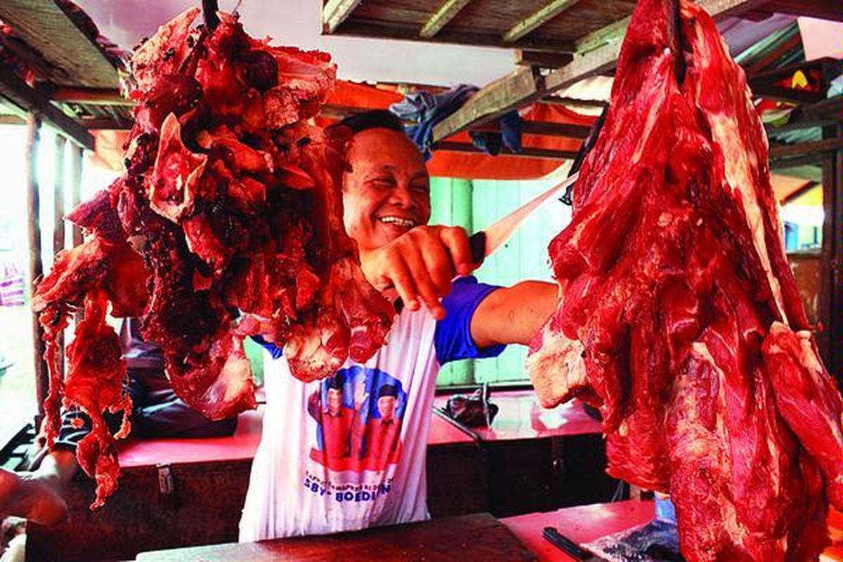 Pedagang daging sapi di Pasar 26 Ilir, Palembang, memotong daging yang digantung di kiosnya, Selasa (1/9). Harga daging sapi di Palembang mulai mengalami kenaikan. Saat ini, harganya Rp 68.000 per kilogram. 