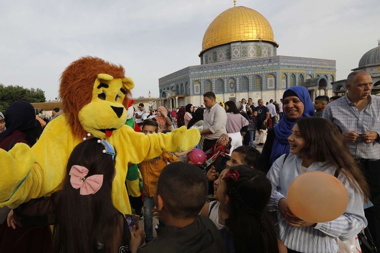 Muslim Palestina tersenyum melihat orang berkostum singa, seusai menunaikan Shalat Id di Kota Tua Yerusalem, 5 Juni 2019.