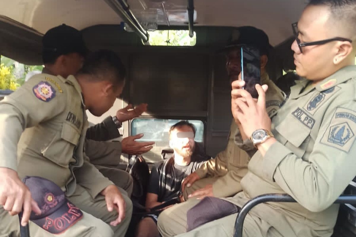 Seorang pria warga negara Rusia, berinisial VK (24), saat diamankan petugas Satpol PP Badung karena mengamuk hingga menceburkan diri ke kolam di sebuah hotel, Banjar Gunung, Desa Buduk  Kecamatan Mengwi, Kabupaten Badung, Bali, pada Rabu (8/2/2023). /Polres Badung